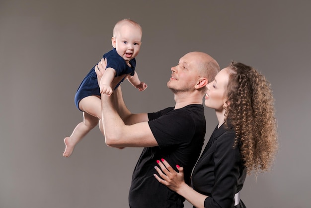 Portrait happy young family dad holds his son in raised arms mom stands next