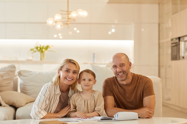 portrait of happy young family lsmiling while helping cute little girl drawing on studying at home