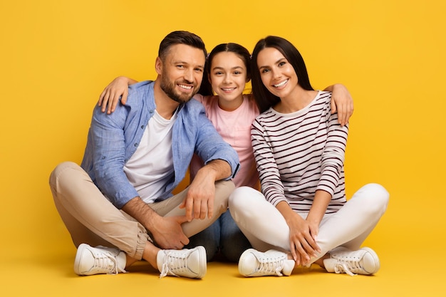 Portrait of happy young family of three with teen daughter