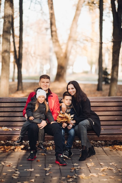 秋の公園で休んでいる子供たちと幸せな若い家族の肖像画。親子関係の概念