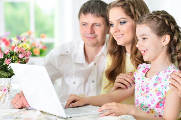 Portrait of happy young family with laptop at home