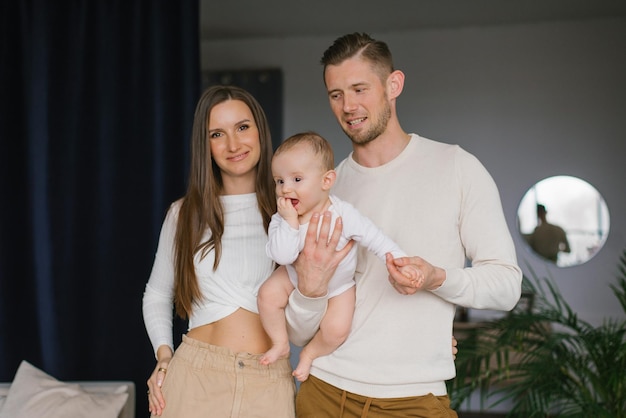 Portrait of a happy young family with their little son in Dads arms in the house