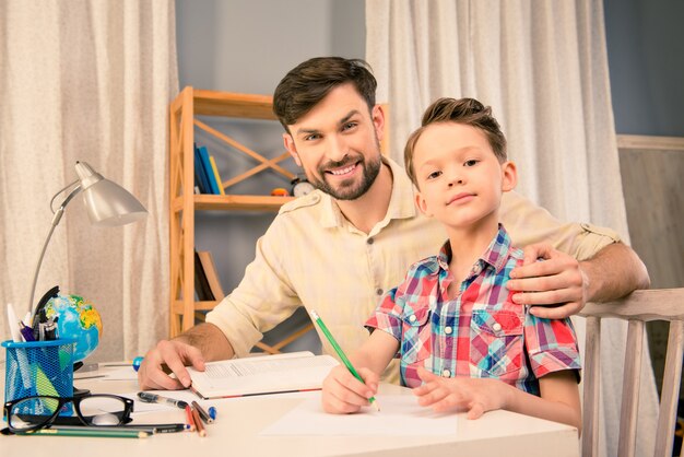 Portrait of happy young father helping his son with homework