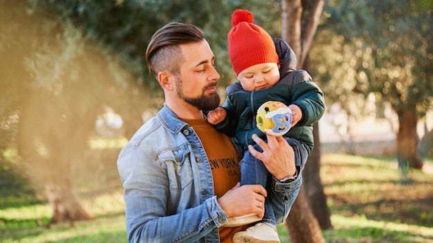 彼の幼い息子を手で保持して幸せな若い父の肖像