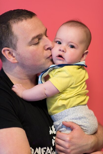 portrait of happy young father holding newborn baby boy isolated on a red background