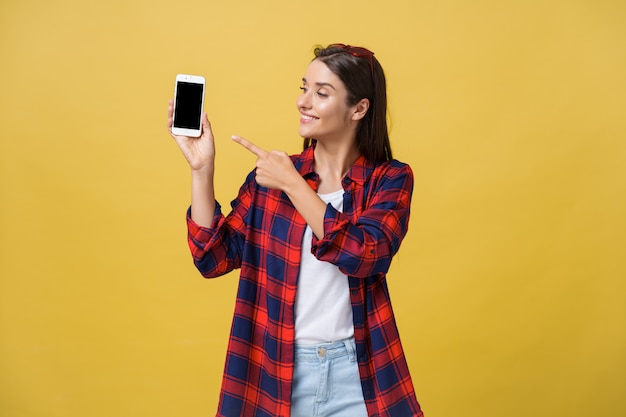 Portrait of a happy young girl dressed in summer pointing finger at blank screen 