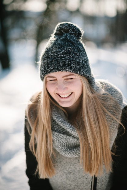 Portrait of a happy young girl jumping and enjoying snow in a winter park.