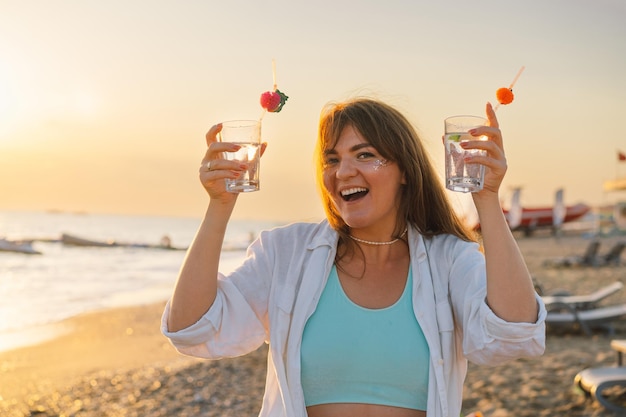 Portrait of a happy young girl with a cocktail in hand on a background of beautiful sea