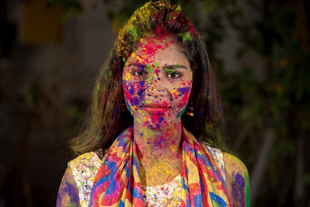 Портрет счастливой молодой девушки с красочным лицом по случаю фестиваля цвета Холи.