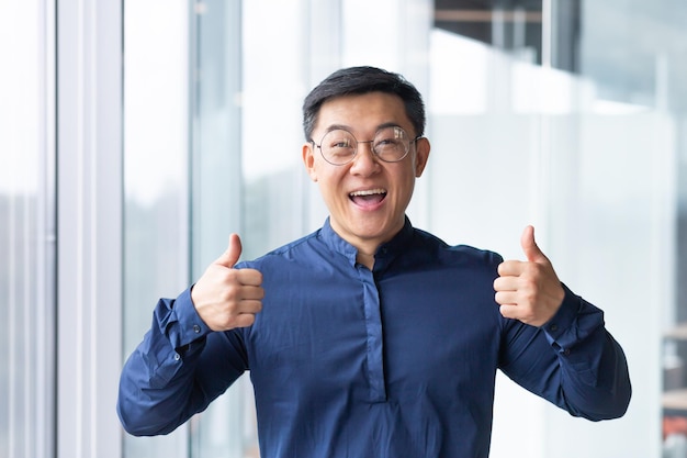 Portrait of a happy young handsome asian man businessman student in glasses and a blue shirt