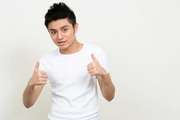 Portrait of happy young handsome Asian man with braces giving thumbs up