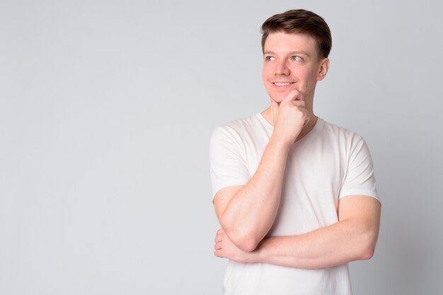 Portrait of happy young handsome man thinking and looking up