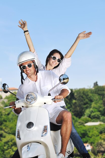 Portrait of happy young love couple on scooter enjoying themselves in a park at summer time