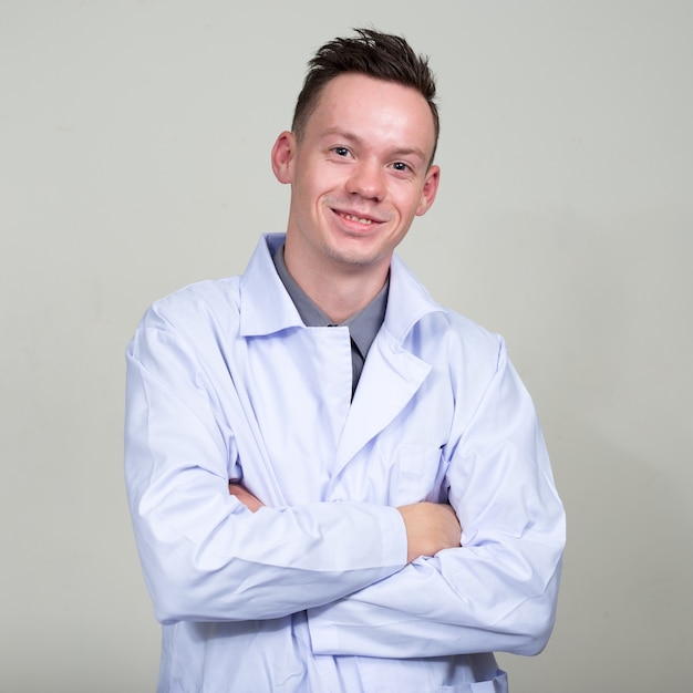 Portrait of happy young man doctor smiling with arms crossed