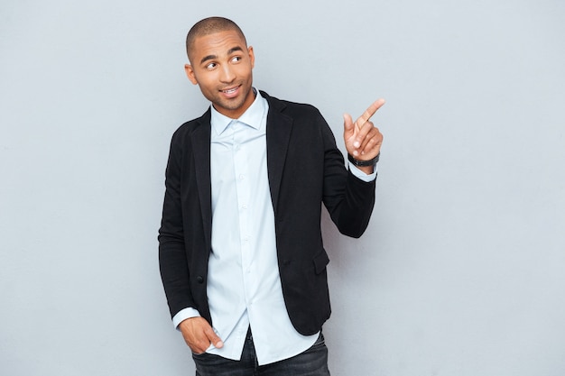 Portrait of a happy young man pointing at something interesting isolated