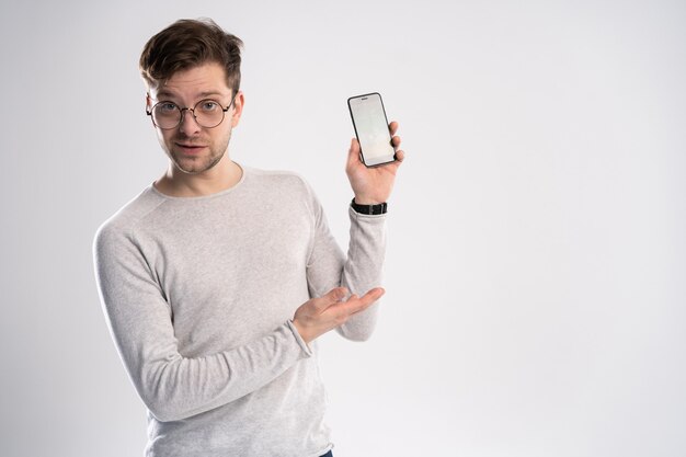 Portrait of happy young man pointing with his finger on the screen of his smartphone