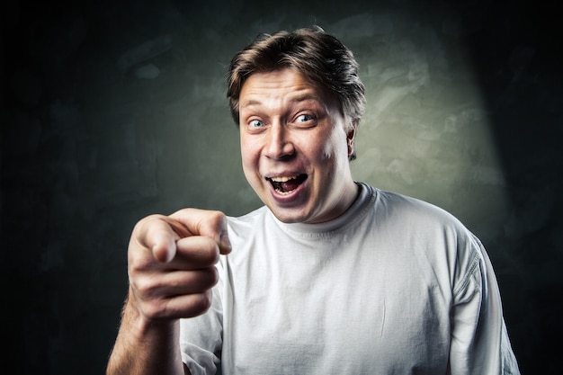 Portrait of happy young man pointing at you over gray background