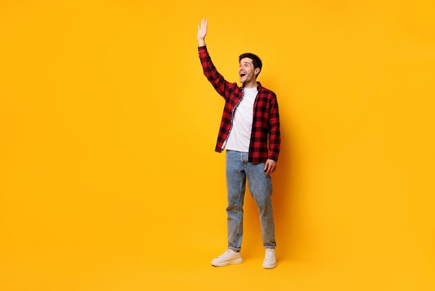 Portrait of happy young man posing at yellow studio