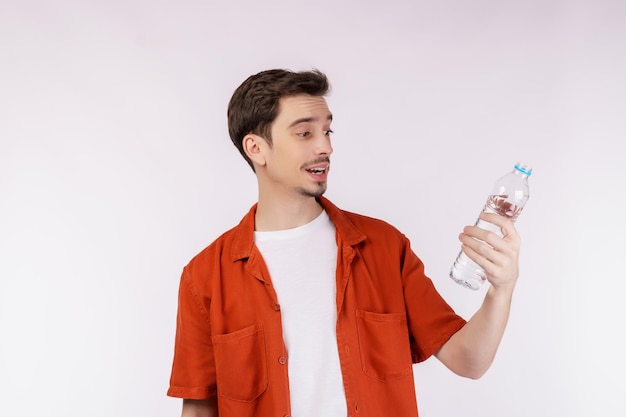 Portrait of Happy young man showing water in a bottle isolated over white background