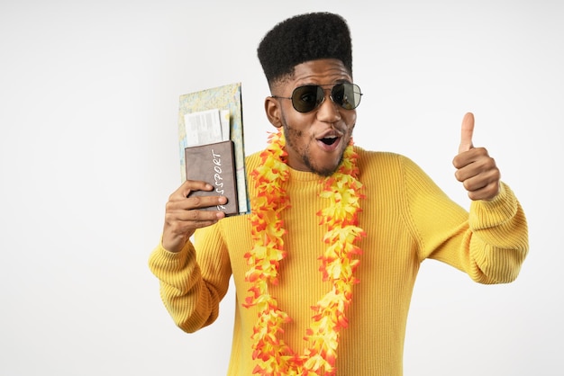 Portrait of happy young man in sunglasses holding passport and tickets and showing thumbs up