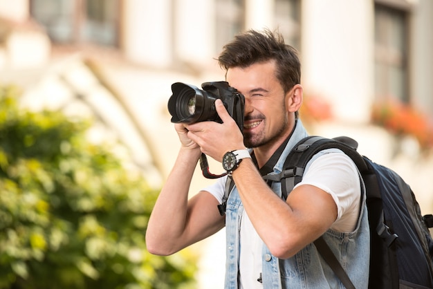 Portrait of happy young man, tourists with camera in city.