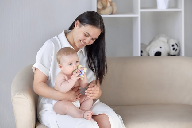 ソファで彼女の幼い息子を抱き締める幸せな若い母親の肖像画。