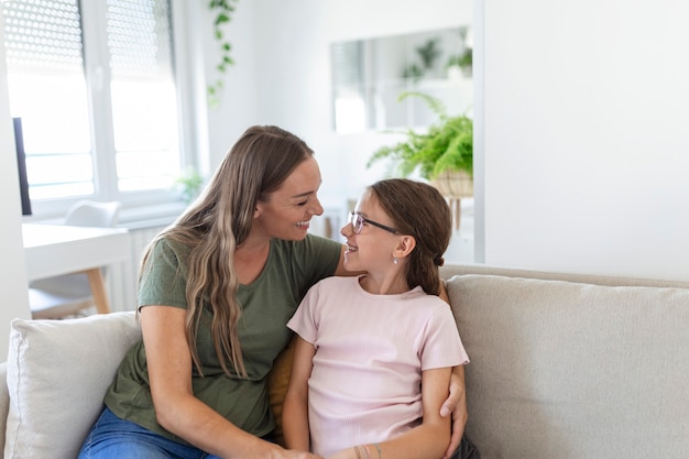 Portrait of happy young mother play hug and cuddle show love cute small preschooler daughter relaxing in living room, smiling mom and little girl child rest enjoy family weekend at home together