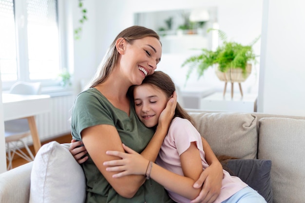 Portrait of happy young mother play hug and cuddle show love cute small preschooler daughter relaxing in living room smiling mom and little girl child rest enjoy family weekend at home together