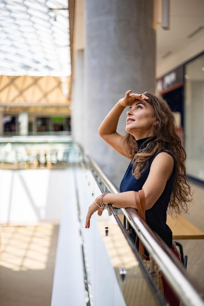 Portrait of happy young stylish shopaholic woman posing at shopping mall center enjoying weekend