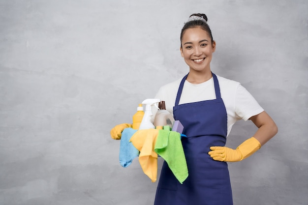 Portrait of a happy young woman cleaning lady in uniform with bucket of cleaning supplies