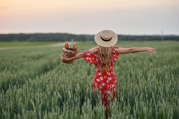 Photo portrait of happy young woman in dress and straw hat holding white bread baguettes