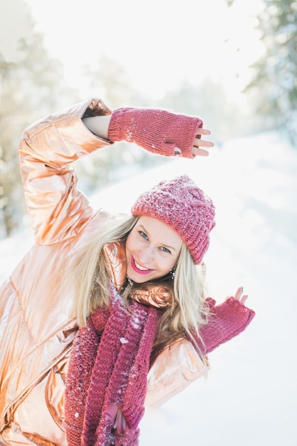 portrait of happy young woman enjoying by trees on snowy field in winter