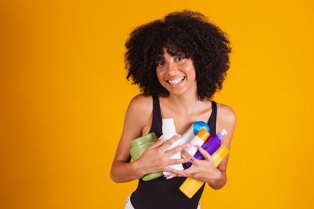 Portrait of happy young woman holding many colorful bottles with different liquids for self care