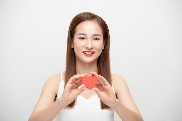 Portrait of a happy young woman holding paper heart isolated over white background