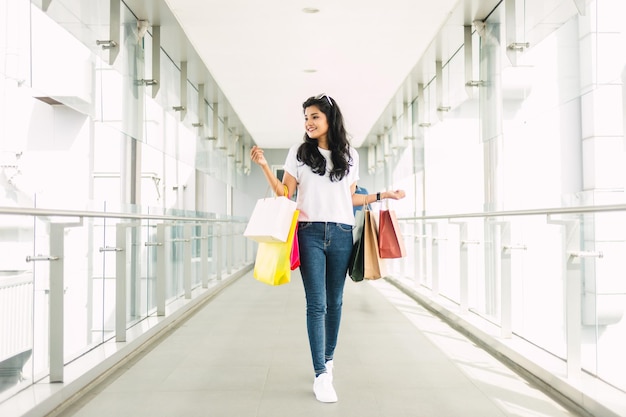 ショッピング モールで買い物袋を保持している幸せな若い女性の肖像画