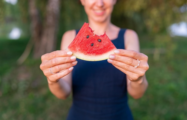 Foto ritratto di una giovane donna felice in possesso di una fetta di anguria e sorridente vacanze estive