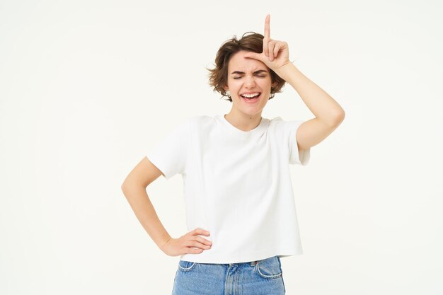 Photo portrait of happy young woman mocking winning prize and making fun of loser showing l letter on                   person