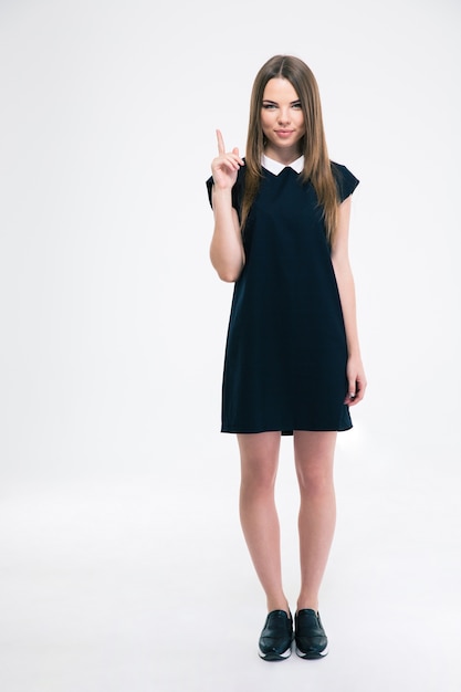Portrait of a happy young woman pointing finger up at copyspace isolated. Looking at camera