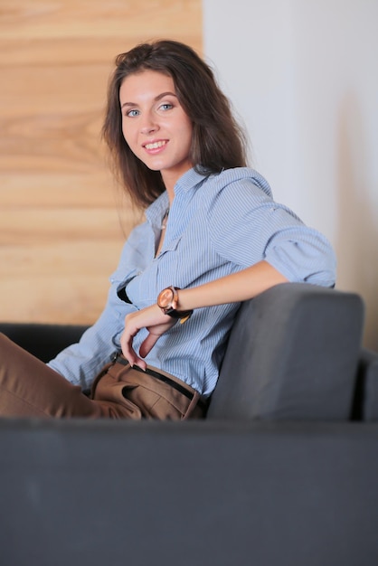 Portrait of happy young woman sitting on sofa