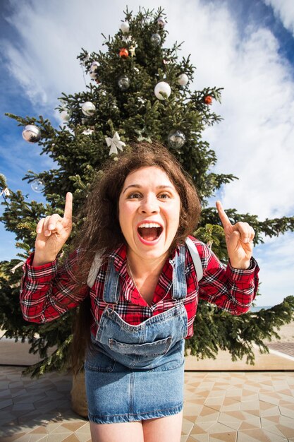 Foto ritratto di una giovane donna felice in piedi vicino a un albero contro il cielo