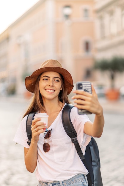 Photo portrait happy young woman taking selfie photo and looking at camera while in the city center