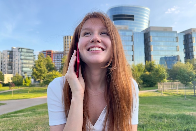 여름에 야외에서 스마트폰으로 전화하는 휴대전화로 말하는 행복한 젊은 여성의 초상화