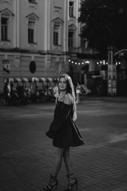 Портрет счастливой молодой женщины в синем платье, смеясь, глядя на камеру, стоящую на улице