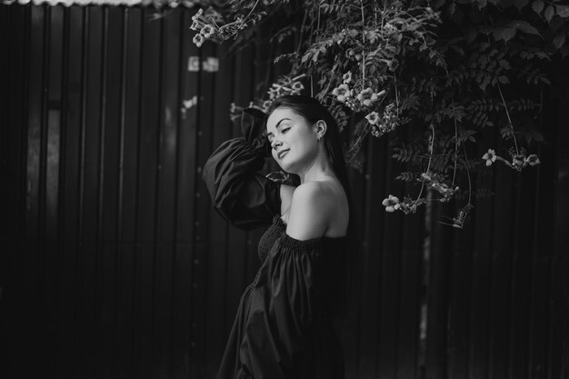 Portrait happy young woman wearing blue dress and standing on campsis radicans flowers