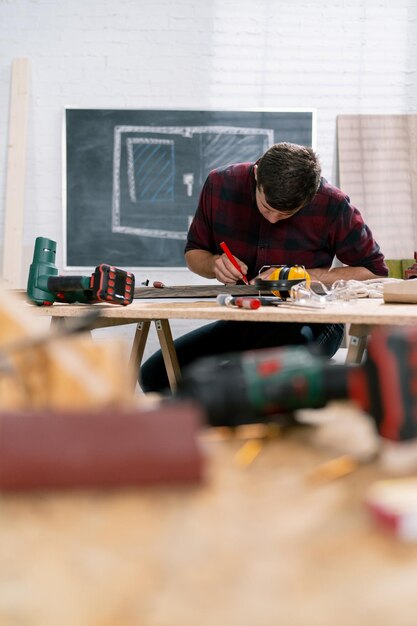 Портрет трудолюбивого профессионального плотника, держащего угловую линейку и карандаш во время измерения