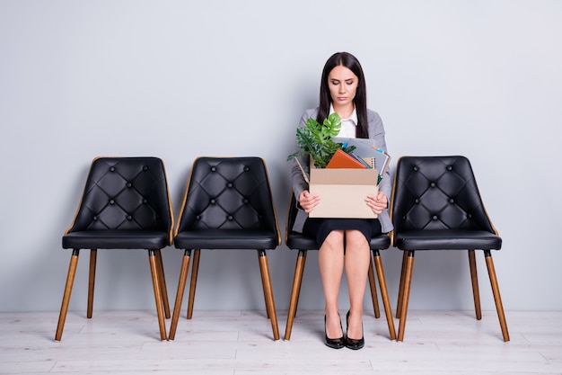 Portrait of her she attractive classy fired jobless lady office manager seeker sitting in chair holding in hands stuff things belongings company cost reduction isolated pastel gray color background