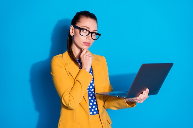 Portrait of her she nice attractive charming chic creative minded lady leader holding in hands laptop thinking planning finance isolated bright vivid shine vibrant blue color background