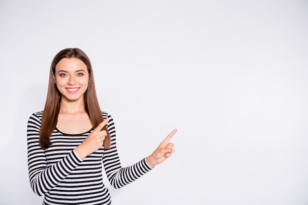 Portrait of her she nice attractive charming lovely cheerful cheery content straight-haired girl pointing two forefingers aside copy space isolated over white light wall