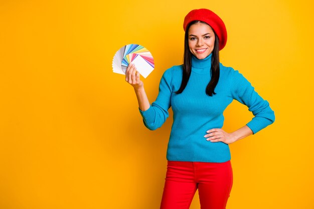 Portrait of her she nice attractive lovely confident cheerful cheery girl designer holding in hand palette different color type styling isolated on bright vivid shine vibrant yellow color wall