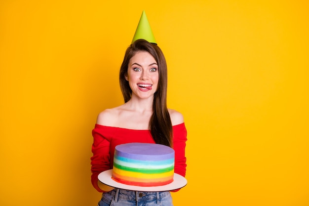 Portrait of her she nice attractive pretty hungry cheerful girl\
holding in hands yummy tasty delicious cake licking lip diet\
calories isolated bright vivid shine vibrant yellow color\
background